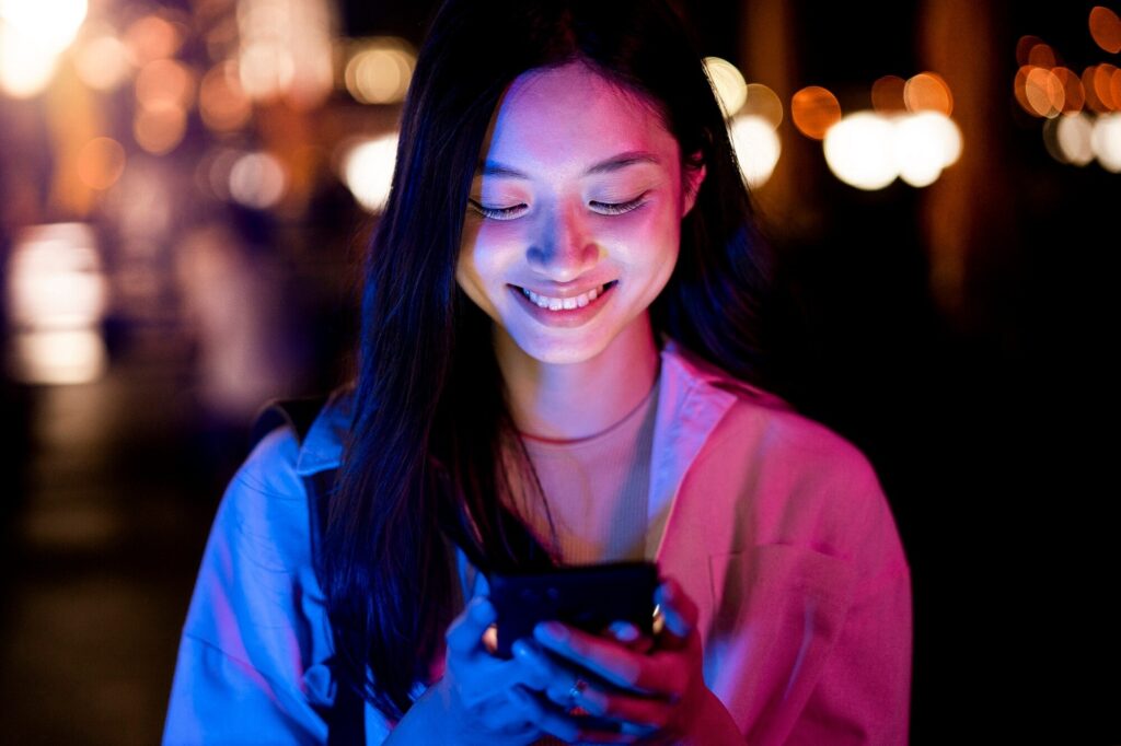 Woman using smartphone at night in the city lights